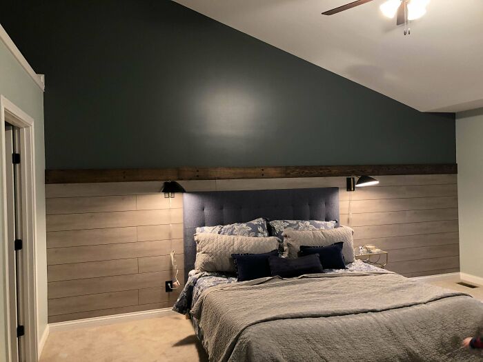 Bedroom with elegant home decoration featuring a blue velvet headboard, wooden accent wall, and minimalist bedside lamps.