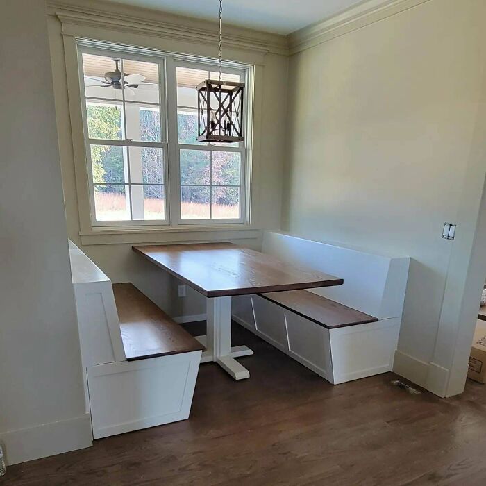 Cozy corner dining area with creative bench seating and wooden table under a modern pendant light.