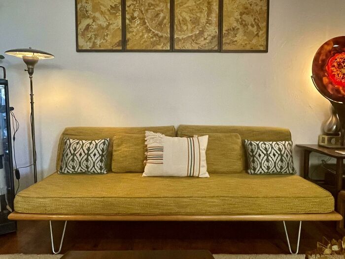 Vintage yellow sofa with decorative pillows in a creatively inspired living room setting.