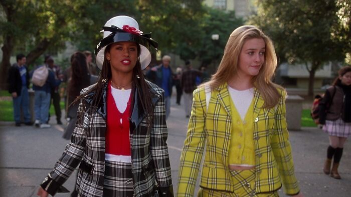 Two friends in iconic 90s fashion walking outside, highlighting iconic friendship duo film scene.