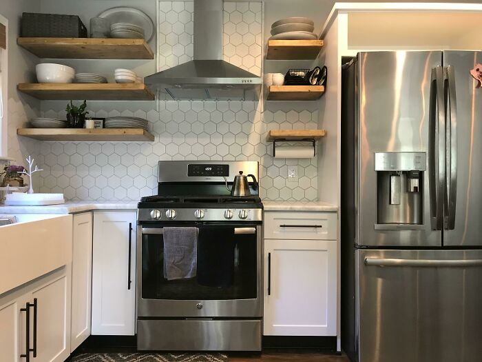 Modern kitchen with stainless steel appliances, hexagonal tile backsplash, and wooden shelves for home decoration ideas.