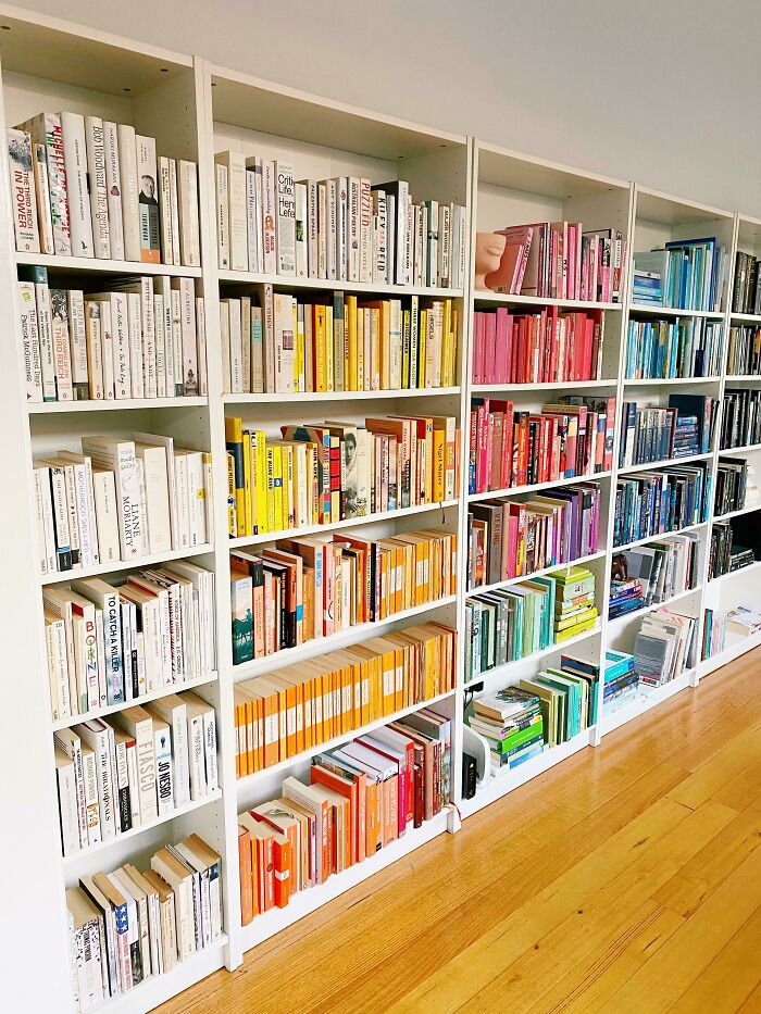 Colorful books arranged by hue on white shelving, creative inspiration for decor ideas.