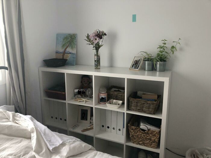 Decorative bookshelf with plants, art, and baskets in a creatively inspired room setting.