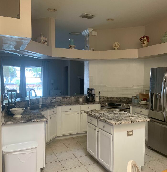 Modern kitchen with white cabinets, marble countertops, and stainless steel appliances for home decoration inspiration.