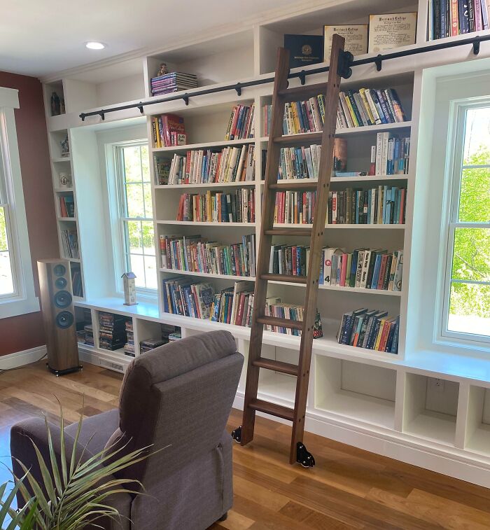 Home decoration idea featuring a cozy bookshelf with a wooden ladder, surrounded by comfortable seating and natural light.