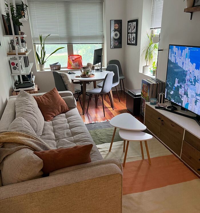 Cozy living room with modern home decoration, featuring a beige sofa, nested tables, and a large TV.