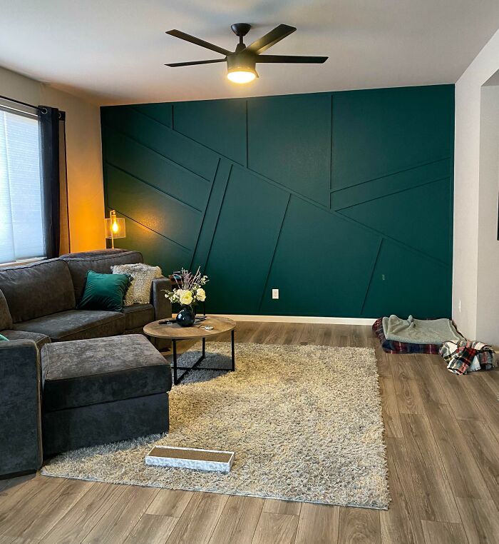 Home decoration idea with a dark teal feature wall, cozy sofa, and modern lighting in a stylish living room.