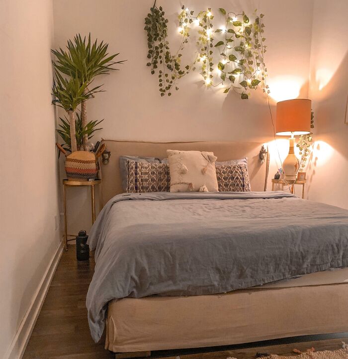Cozy bedroom with creative decoration, featuring string lights and leafy vines above the headboard for inspiration.