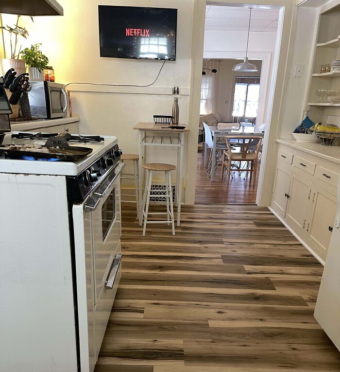 Small kitchen with wood flooring, white cabinets, and a wall-mounted TV for home decoration ideas.