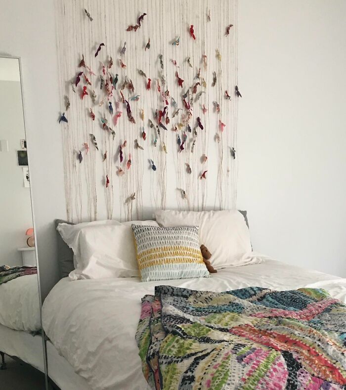 Creative decoration idea with colorful hanging art over a cozy bed, inspiring creative inspiration.