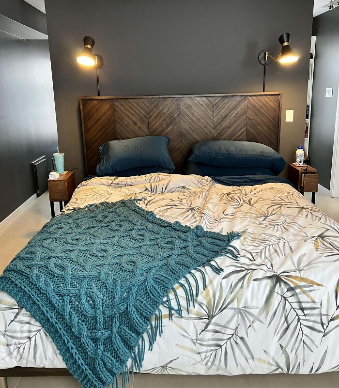 Cozy bedroom decor with modern lighting and a teal knit throw on a floral bedspread.