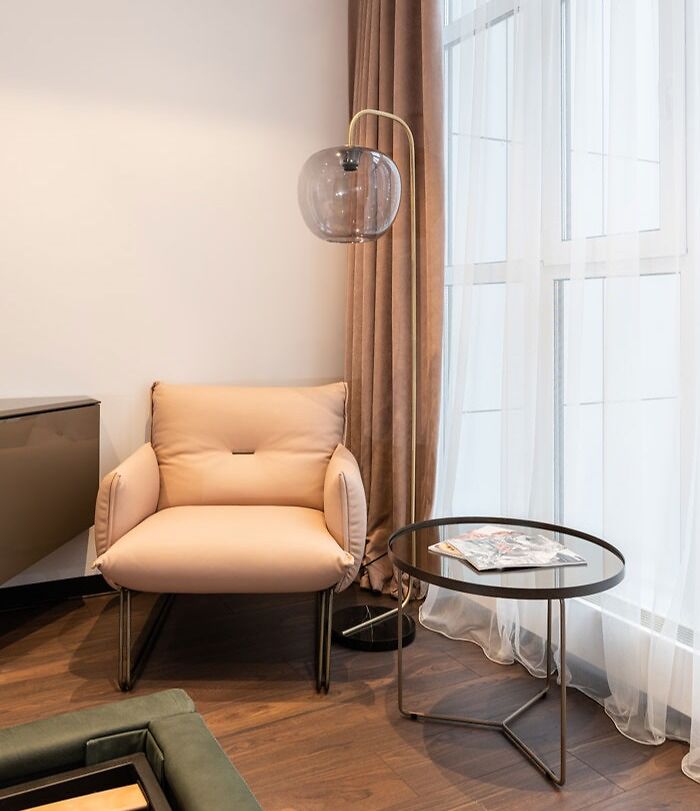 Modern living room corner with beige armchair and round table, featuring stylish home decoration elements.