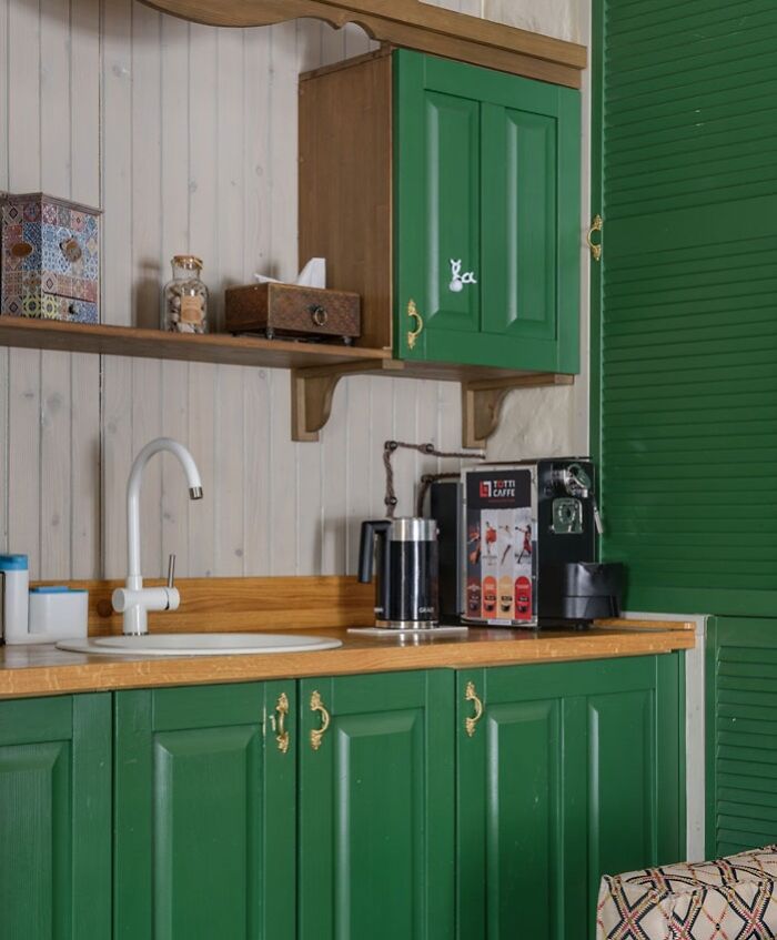 Creative kitchen decoration with green cabinets, wooden shelves, and coffee maker for inspiration.