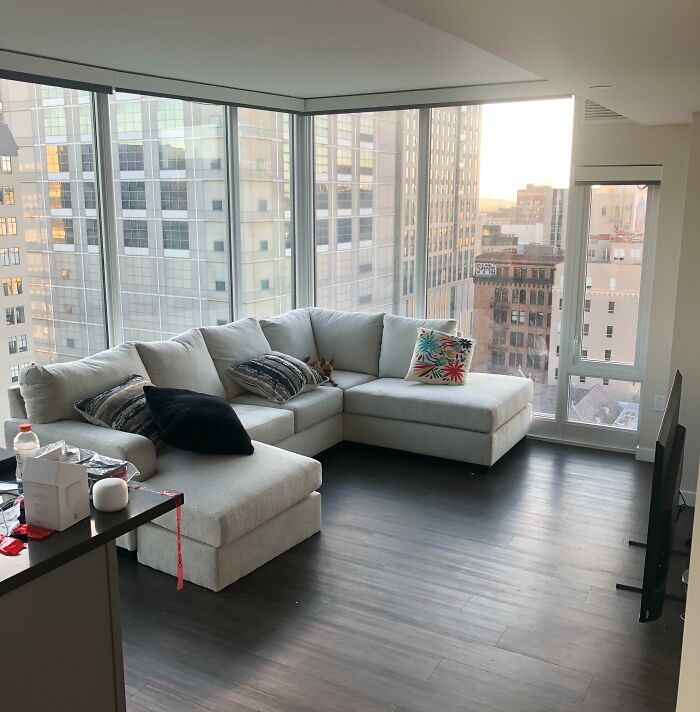 Modern living room with large windows, featuring an elegant sectional sofa with colorful pillows, enhancing home decoration.