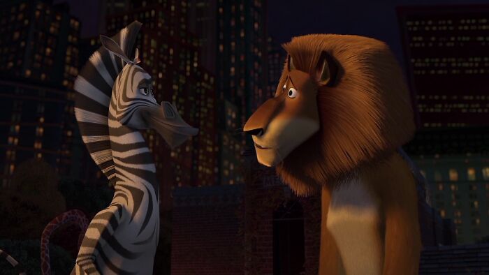 Zebra and lion from an iconic best friend duo in an animated cityscape scene at night.
