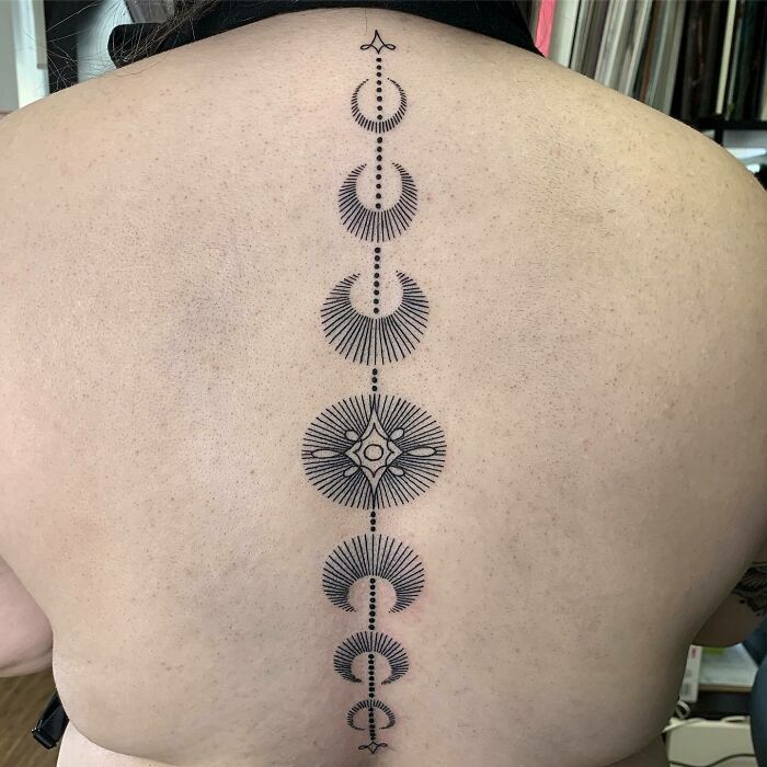 Decorative spine tattoo with geometric designs on a person's back.