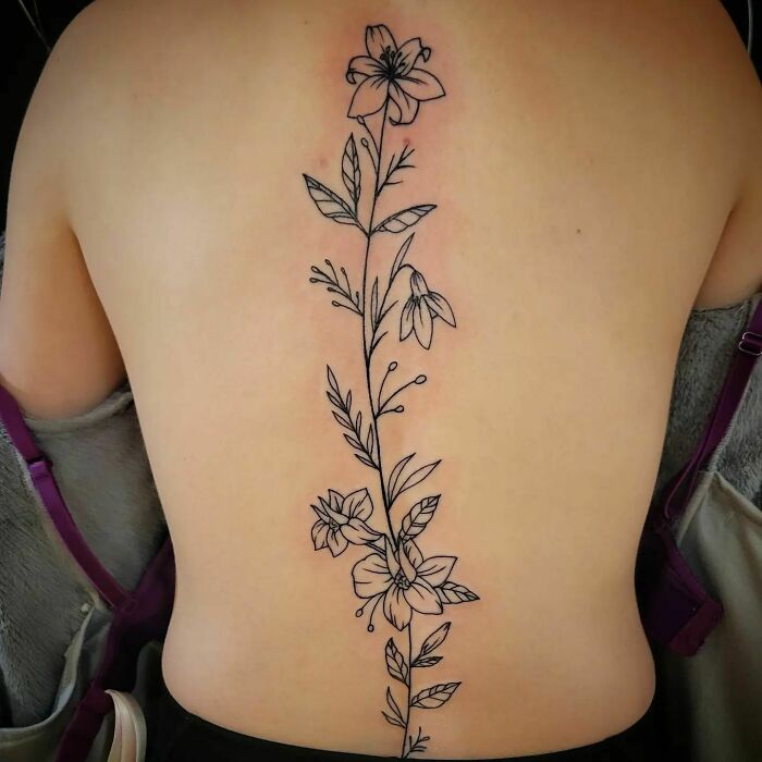 Floral spine tattoo design with delicate line work along the back.