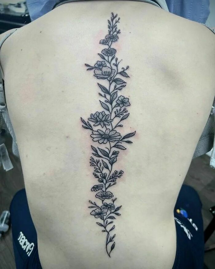 Floral spine tattoo featuring intricate black linework on a person's back.
