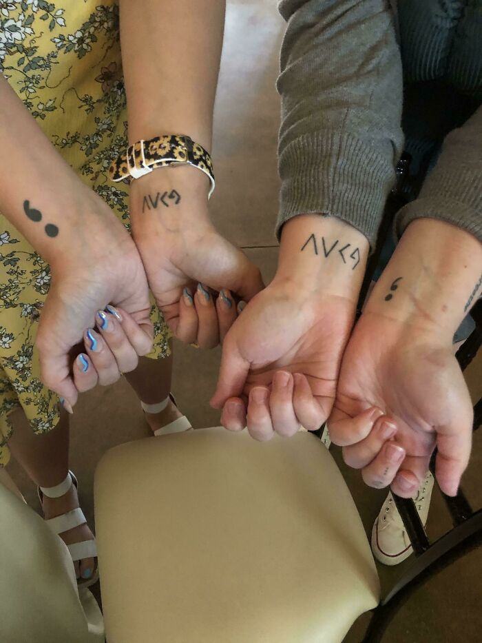 Three wrists with tattoos: symbols and semicolons, showcasing unique wrist tattoo ideas.