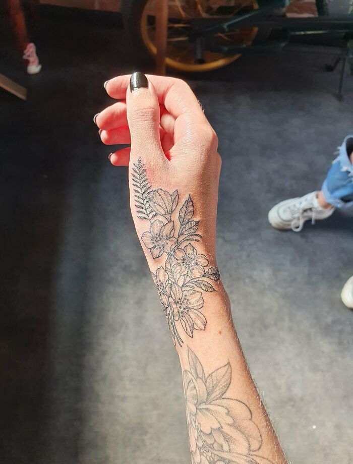 Floral wrist tattoo design on a person's arm, showcasing intricate flower and leaf patterns.