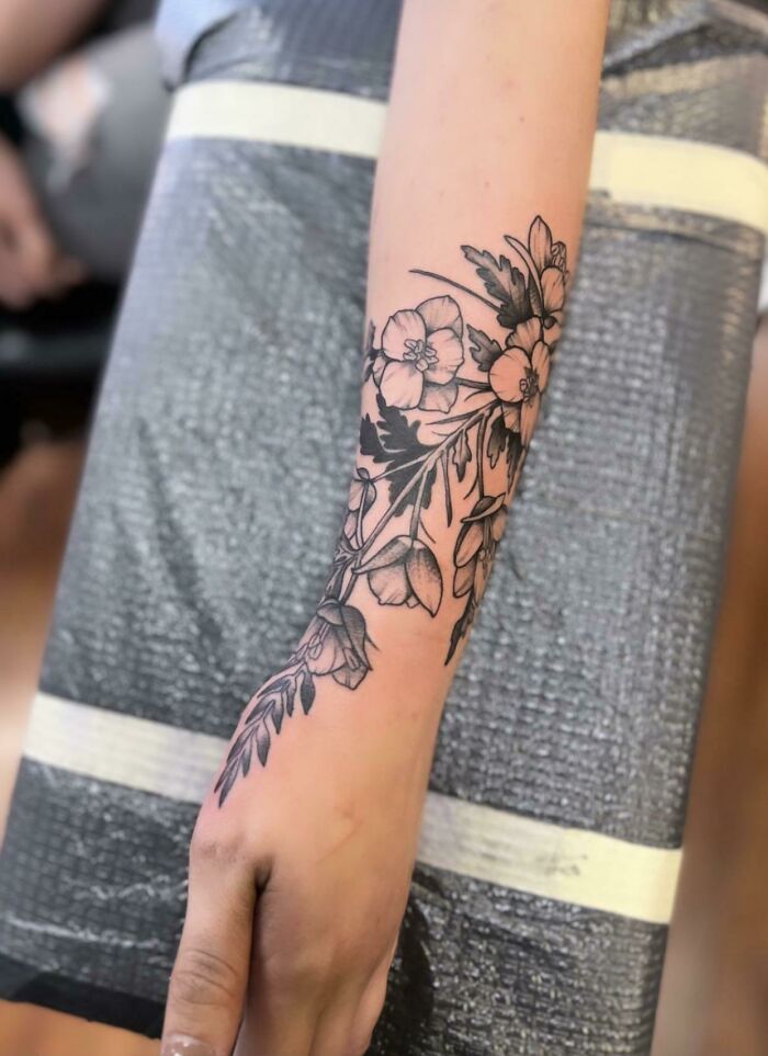 Floral wrist tattoo design showing intricate black ink detailing.