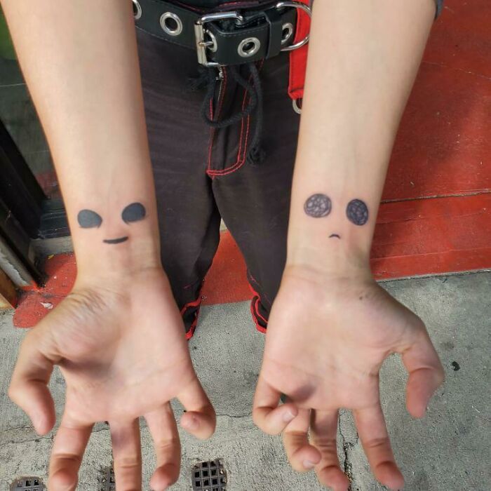 Minimalist wrist tattoos with happy and sad faces on both wrists, expressing contrasting emotions.