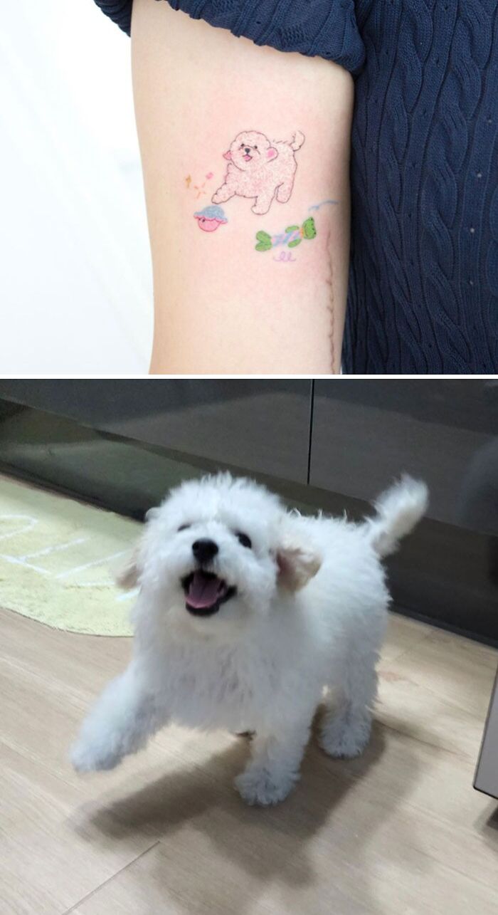 Arm with an animal tattoo of a fluffy dog next to a real playful white dog.