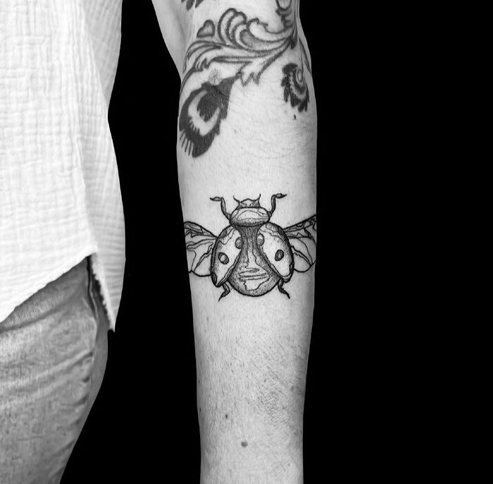 Black and white ladybug tattoo design on arm showcasing animal tattoo inspiration.