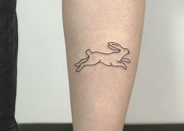 Minimalist rabbit outline tattoo on forearm, showcasing animal tattoo inspiration.