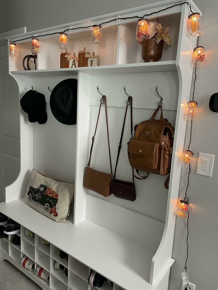 White entryway organizer decorated with warm string lights and accessories.