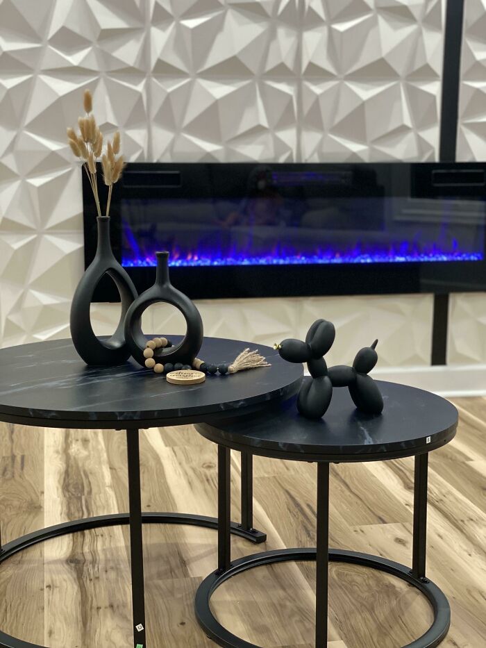 Black decorative vases and a balloon dog sculpture on round tables against a geometric wall, enhancing home decoration.