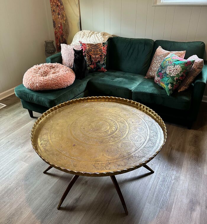 Elegant home decoration with a green sofa, decorative pillows, and an ornate brass table in a cozy living room.