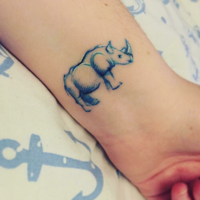 Wrist tattoo design of a blue rhino on human skin.
