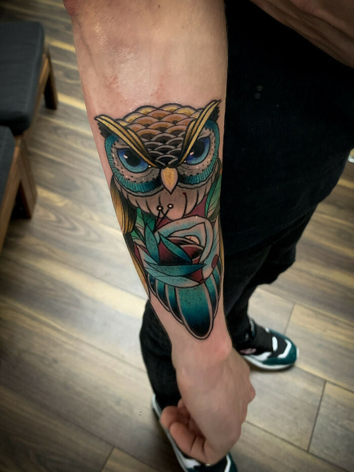 Colorful owl wrist tattoo with vibrant details on forearm.