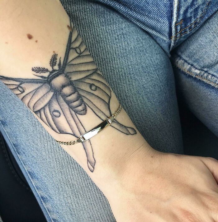 Moth wrist tattoo with a gold bracelet, showcasing unique tattoo ideas.