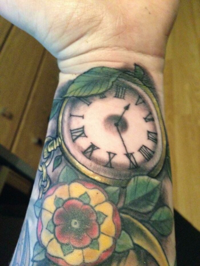 Wrist tattoo featuring a vintage clock and colorful floral design.