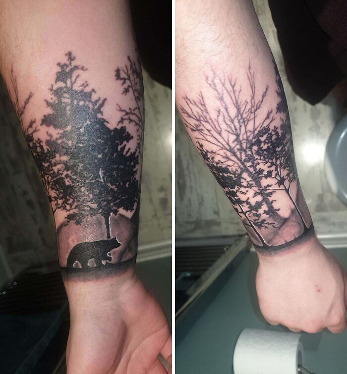 Wrist tattoo design featuring a forest scene with trees and a bear silhouette.