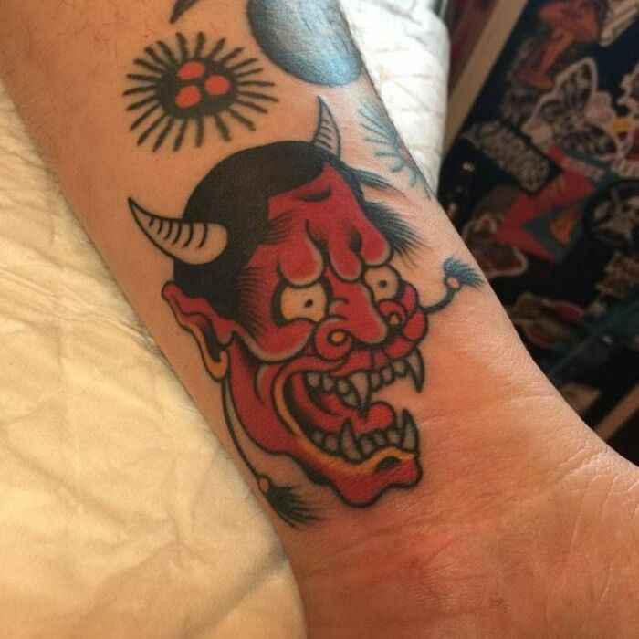 Bold red demon wrist tattoo, showcasing intricate design and vivid colors.
