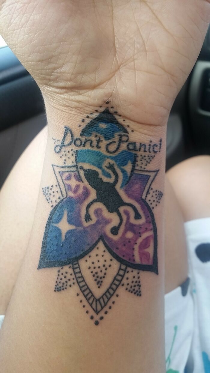 "Wrist tattoo with 'Don't Panic' text and colorful design, making a bold statement."
