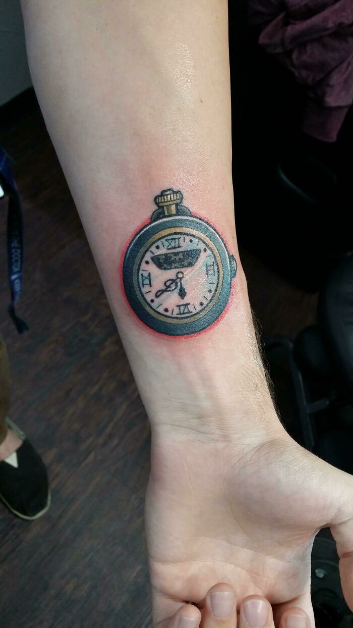 Wrist tattoo of a pocket watch with Roman numerals, making a statement.