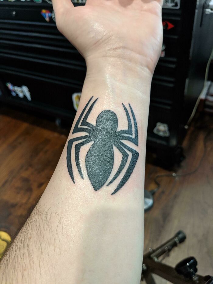 Wrist tattoo with a black spider design.