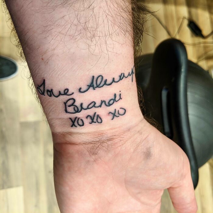 Wrist tattoo with cursive script saying "Love Always Brandi XO XO XO" in a personal message style.