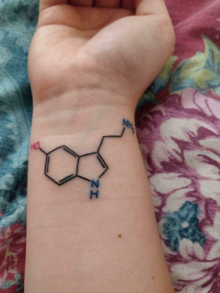 Chemical structure wrist tattoo design on an arm.