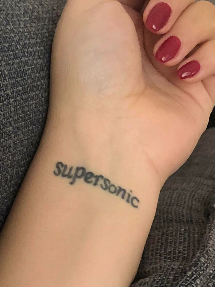 "Wrist tattoo with 'Supersonic' in black ink, showcasing a bold statement design."