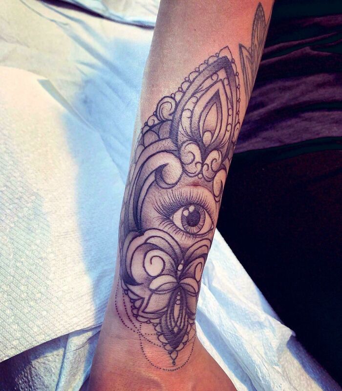 Ornate eye-themed wrist tattoo design featuring intricate patterns and shading.