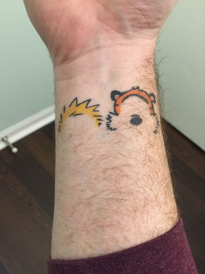 Colorful wrist tattoo design featuring cartoon characters.