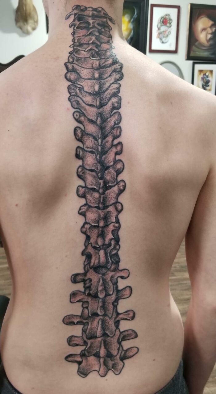 Elegant spine tattoo design on person's back, featuring detailed vertebrae art.