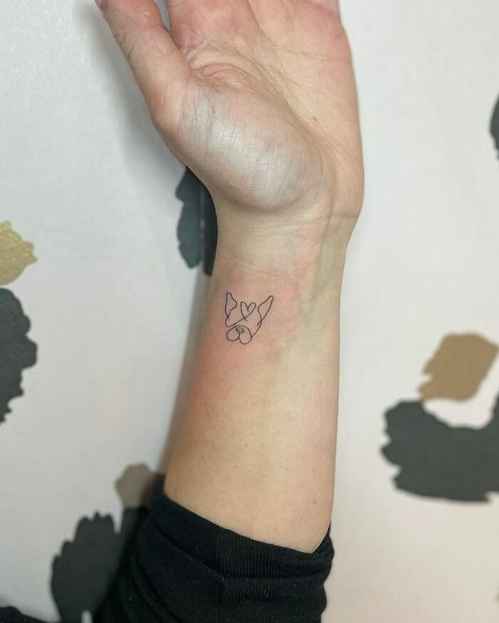 Minimalist wrist tattoo of two French Bulldogs with a heart, showcasing a unique tattoo idea.