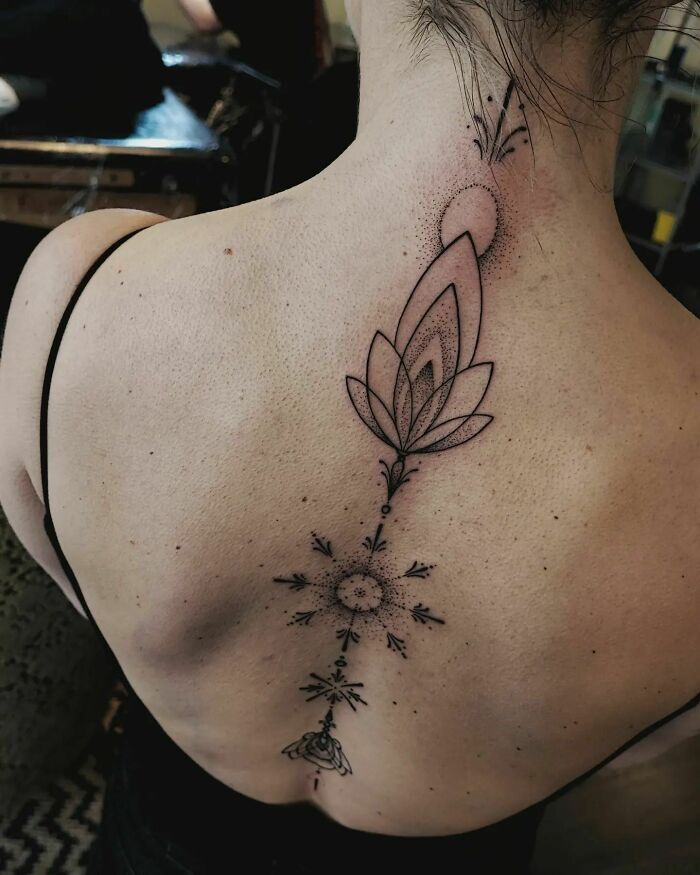 Delicate spine tattoo featuring intricate floral design along the upper back.