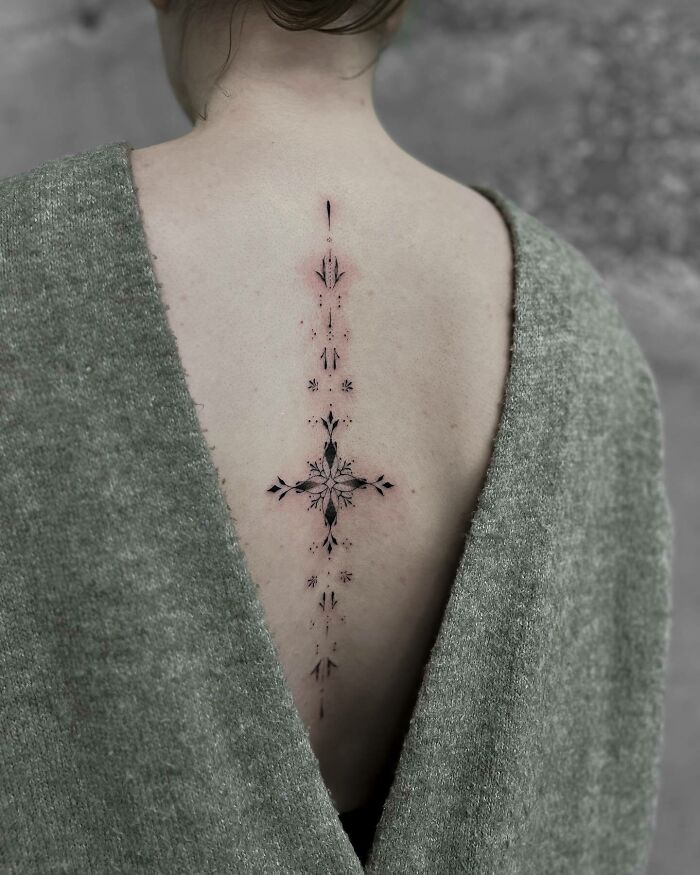 Elegant spine tattoo design on a woman's back, featuring intricate details and symmetrical patterns.